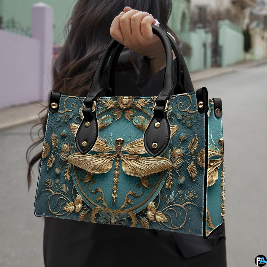 Street lifestyle view of model carrying gold dragonfly handbag by the top handle