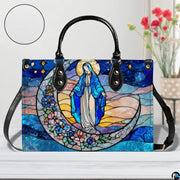 Stained glass Marian handbag shown on white wooden surface with texture swatch and background floral vase.