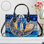 Stained glass Marian handbag shown on white wooden surface with texture swatch and background floral vase.