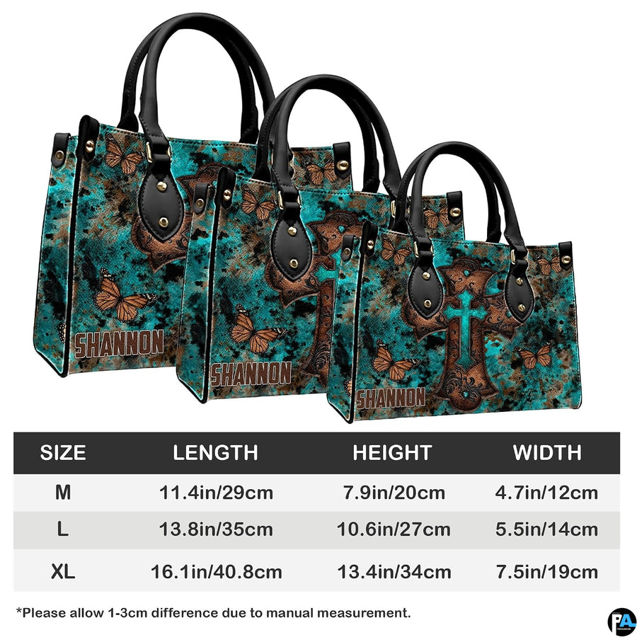 Angled perspective view of turquoise cross butterfly handbag highlighting rustic patina artwork.