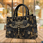 Angled perspective view of gold dragonfly handbag resting on a rustic wooden tabletop near a window