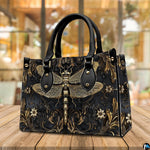 Angled perspective view of gold dragonfly handbag resting on a rustic wooden tabletop near a window