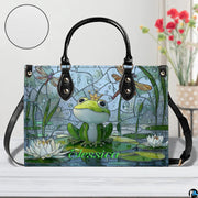 Angle perspective view of the frog handbag displaying side depth and printed pond scene.