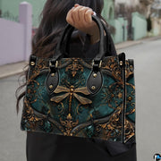 Front view of Victorian baroque dragonfly handbag featuring gold filigree cartouche on dark teal