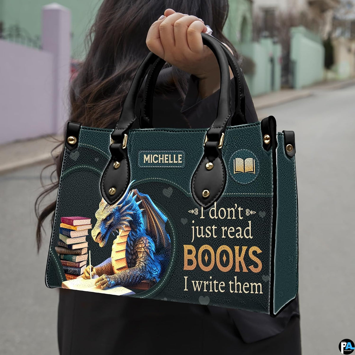 Author blue dragon handbag carried outdoors by top handle along residential street.