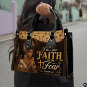 Handbag held outdoors showing prayerful woman graphic and cross border