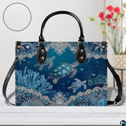 Perspective angle view of sea turtle handbag emphasizing decorative print and structured silhouette.