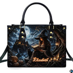 Gothic witch satchel showing seated sorceress reading glowing spellbook with black cat and cliffside castle under full moon.
