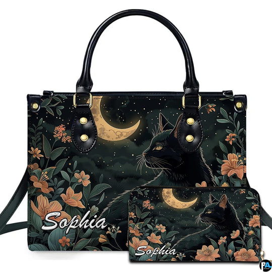 Black cat profile looking toward a golden crescent moon amid peach floral blooms.