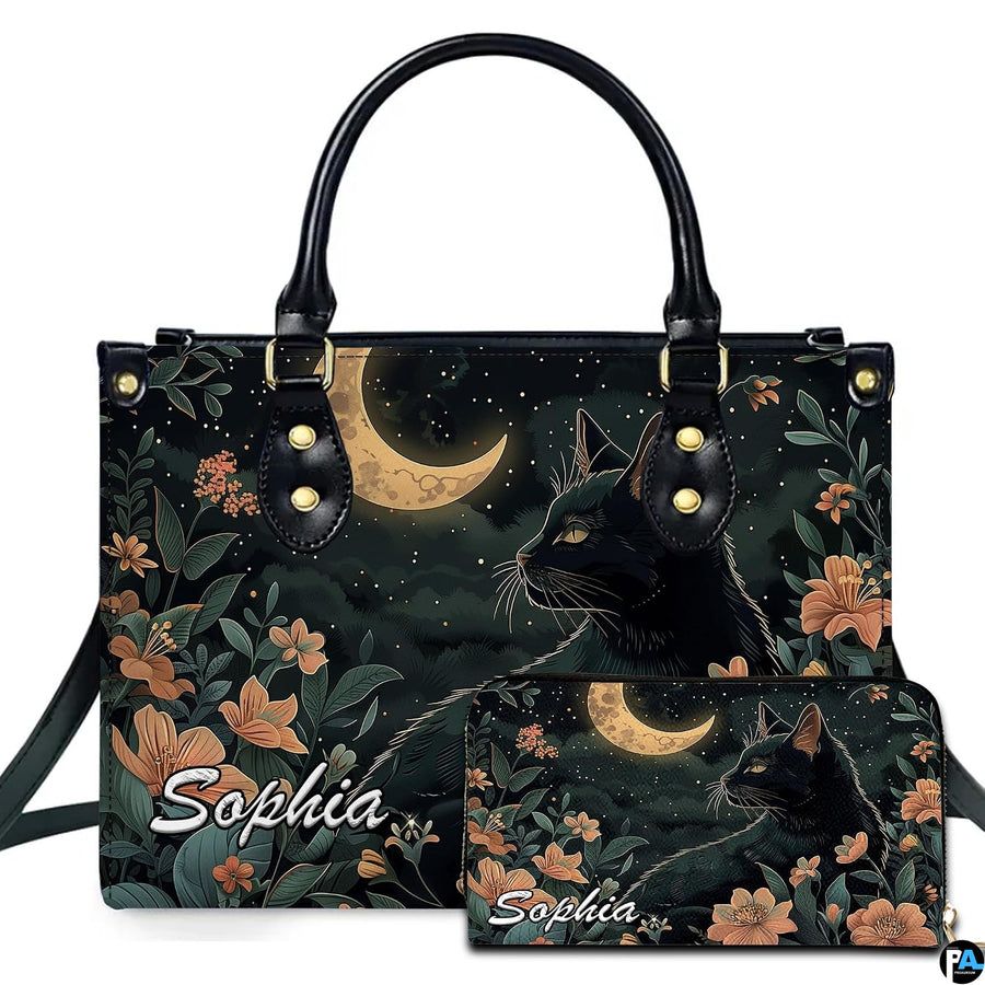 Black cat profile looking toward a golden crescent moon amid peach floral blooms.
