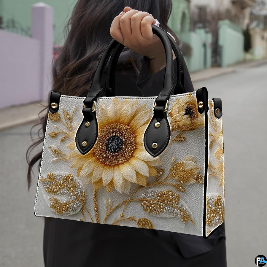Side profile of sunflower handbag showing structured silhouette and black carrying handles.